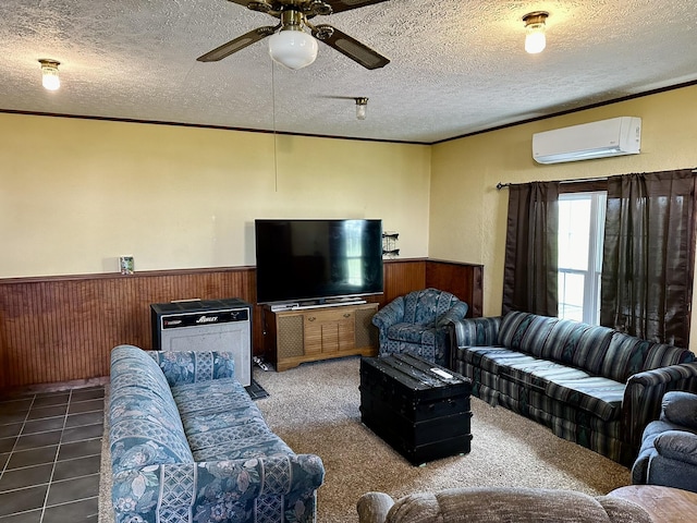 living area with a wall unit AC, ceiling fan, crown molding, a wainscoted wall, and a textured ceiling