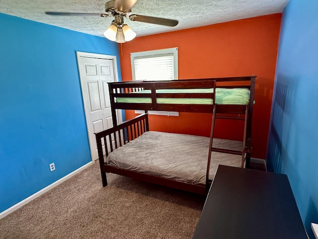 carpeted bedroom featuring a textured ceiling, a closet, a ceiling fan, and baseboards