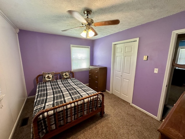 carpeted bedroom featuring a textured ceiling, ceiling fan, visible vents, a closet, and baseboards