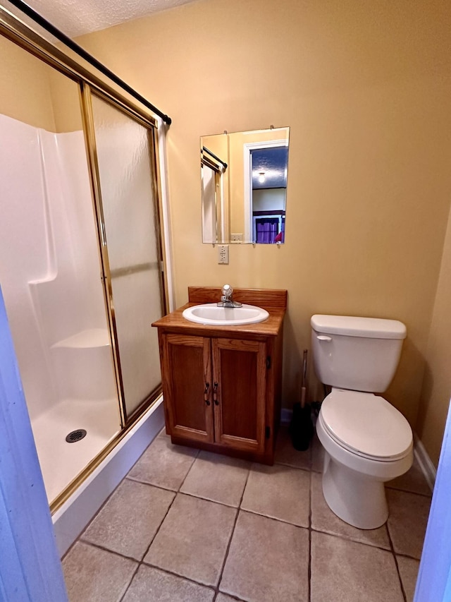 full bathroom with vanity, toilet, a stall shower, a textured ceiling, and tile patterned flooring
