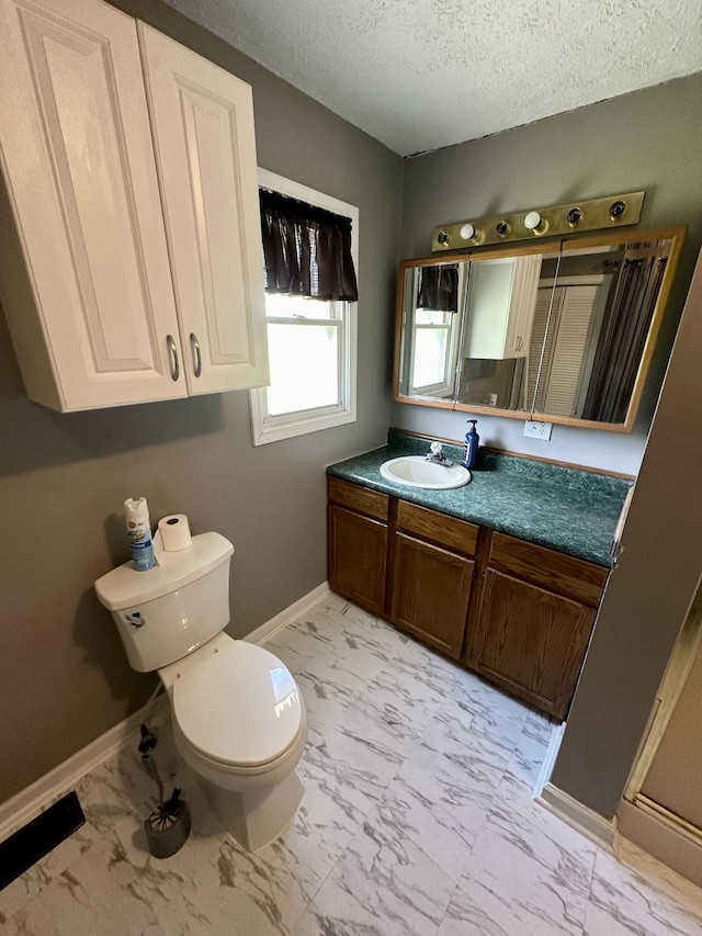 bathroom featuring marble finish floor, toilet, vanity, baseboards, and a textured ceiling