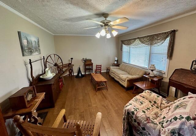 living room with wood finished floors, ceiling fan, a textured ceiling, and crown molding