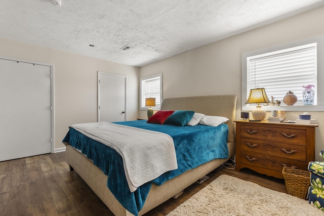 bedroom featuring visible vents, a textured ceiling, and wood finished floors