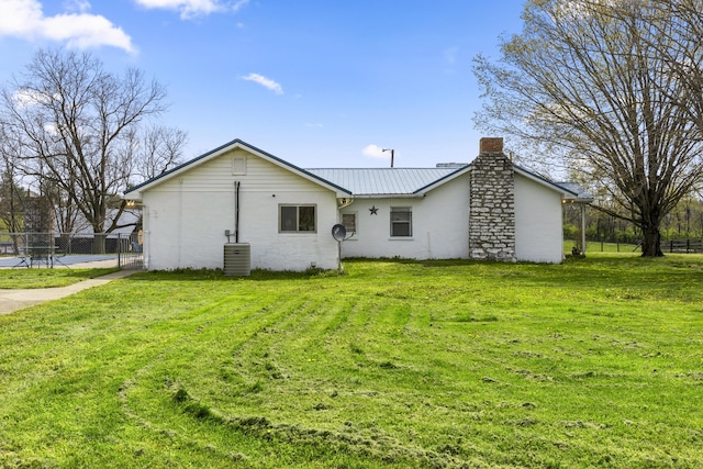 back of house featuring fence, a yard, and a chimney
