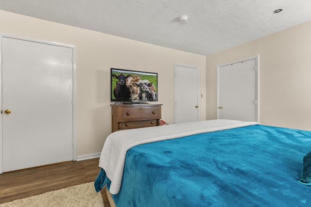 bedroom featuring baseboards, a textured ceiling, and wood finished floors