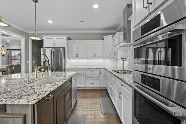 kitchen featuring white cabinets, wall chimney exhaust hood, stainless steel appliances, and a sink