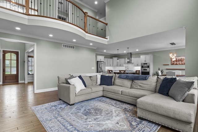 living area with visible vents, an inviting chandelier, recessed lighting, a high ceiling, and crown molding