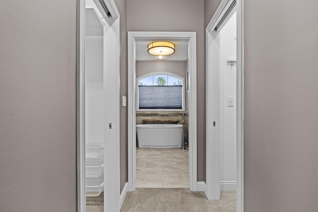 hallway featuring carpet flooring and baseboards