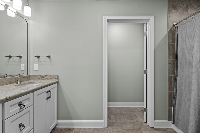 full bath featuring a tile shower, baseboards, and vanity