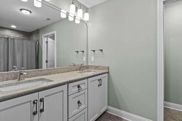 full bath featuring baseboards, visible vents, a sink, and double vanity