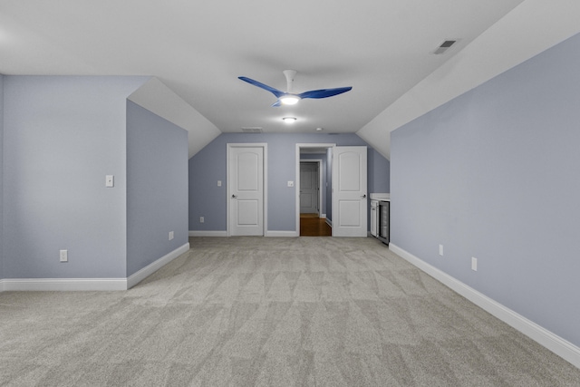 additional living space with light colored carpet, ceiling fan, vaulted ceiling, and visible vents