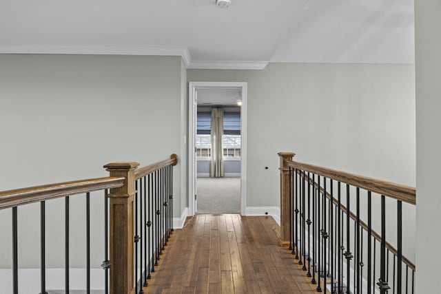 corridor featuring dark wood finished floors, crown molding, baseboards, and an upstairs landing