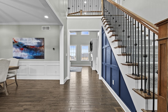 entryway featuring dark wood finished floors, a towering ceiling, visible vents, stairway, and ornamental molding