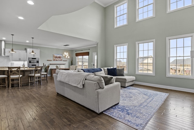 living area with baseboards, ornamental molding, dark wood-type flooring, and recessed lighting