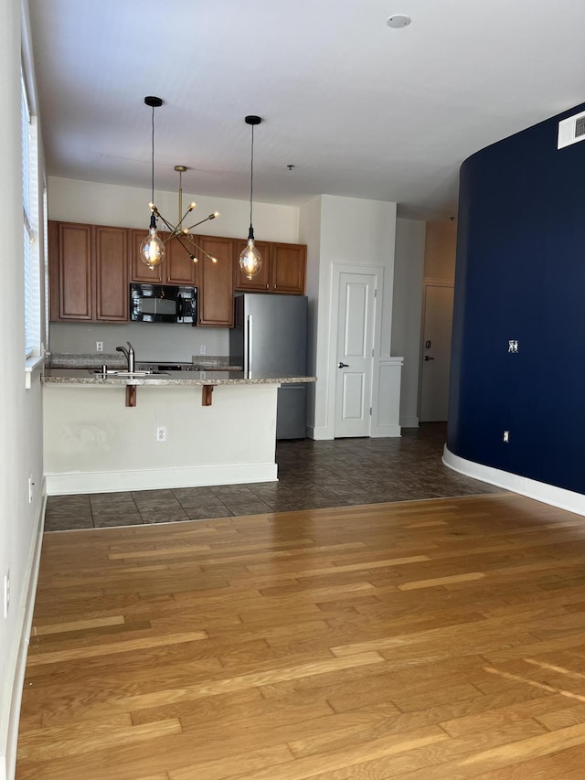 650 S Mill St Unit 218, Lexington, KY 40508 - kitchen featuring black microwave, freestanding refrigerator, a kitchen breakfast bar, wood finished floors, and a peninsula