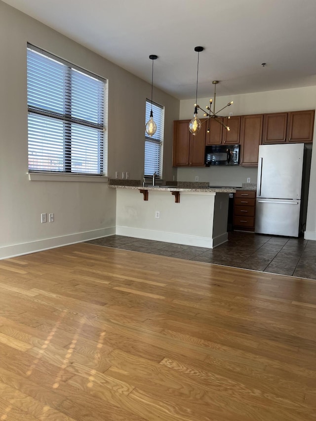 650 S Mill St Unit 218, Lexington, KY 40508 - kitchen featuring freestanding refrigerator, black microwave, dark wood-type flooring, a breakfast bar, and baseboards