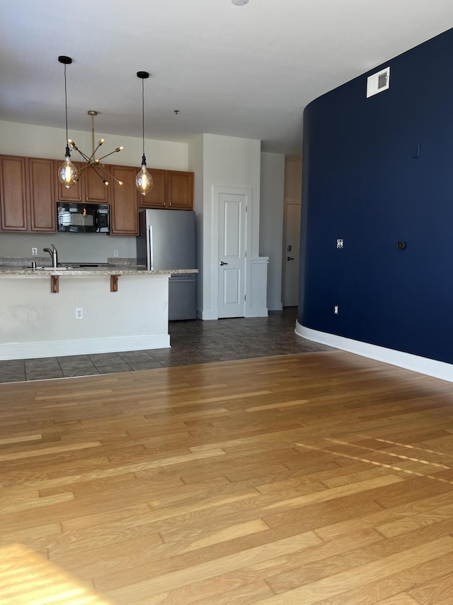 650 S Mill St Unit 218, Lexington, KY 40508 - kitchen with black microwave, a breakfast bar area, hanging light fixtures, light wood finished floors, and freestanding refrigerator