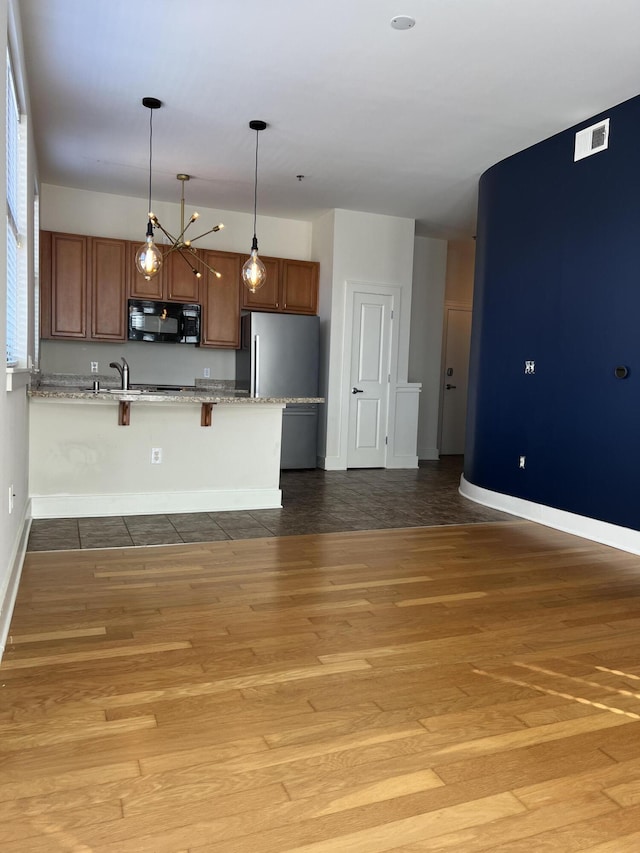 650 S Mill St Unit 218, Lexington, KY 40508 - kitchen with black microwave, a peninsula, a kitchen bar, baseboards, and wood finished floors