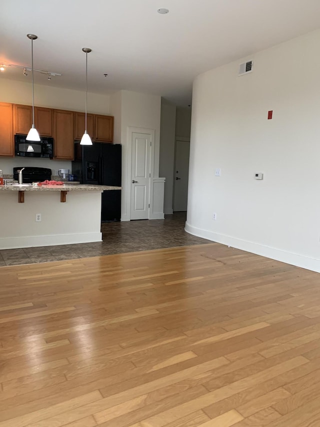 650 S Mill St Unit 218, Lexington, KY 40508 - kitchen featuring black appliances, a kitchen breakfast bar, light wood-style flooring, and baseboards