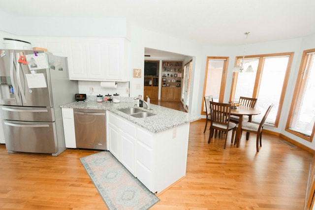 kitchen with white cabinets, appliances with stainless steel finishes, a sink, and light wood-type flooring