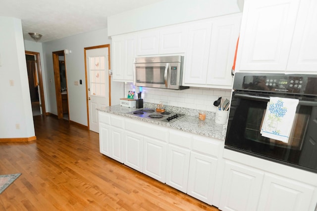 kitchen with white cabinets, tasteful backsplash, light wood-type flooring, and stainless steel appliances