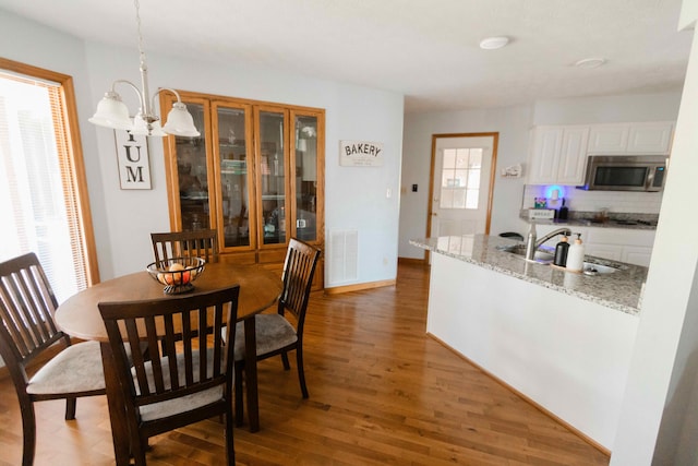 dining space featuring light wood-style flooring, visible vents, baseboards, and a notable chandelier