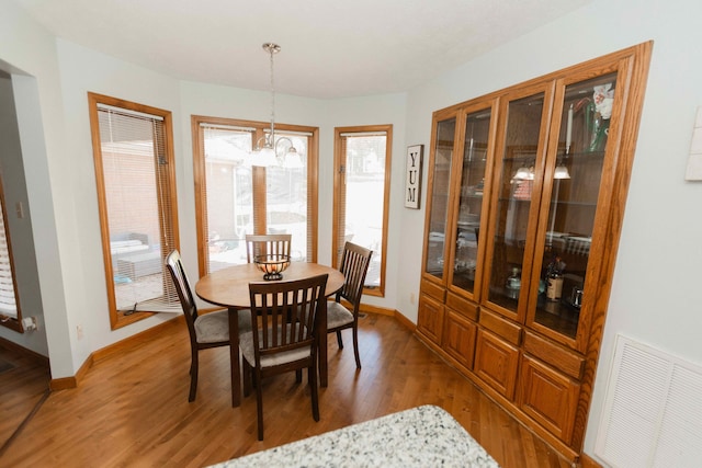 dining room with baseboards, a notable chandelier, visible vents, and light wood-style flooring