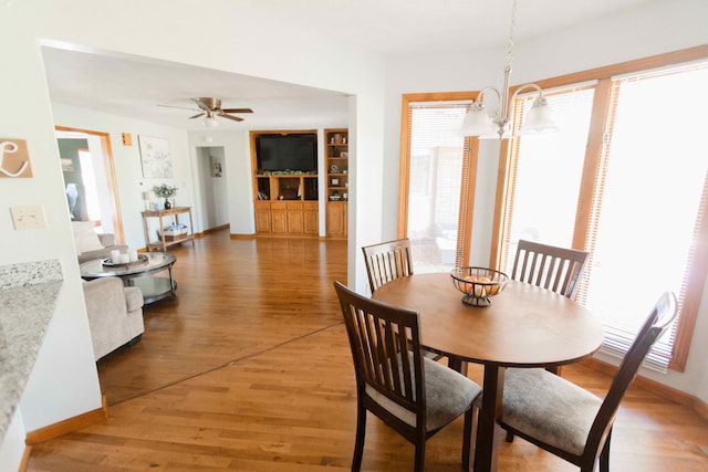 dining room featuring light wood-style flooring, a healthy amount of sunlight, baseboards, and ceiling fan