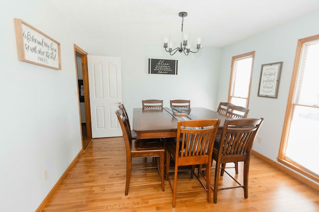dining room with light wood-type flooring, baseboards, and a chandelier