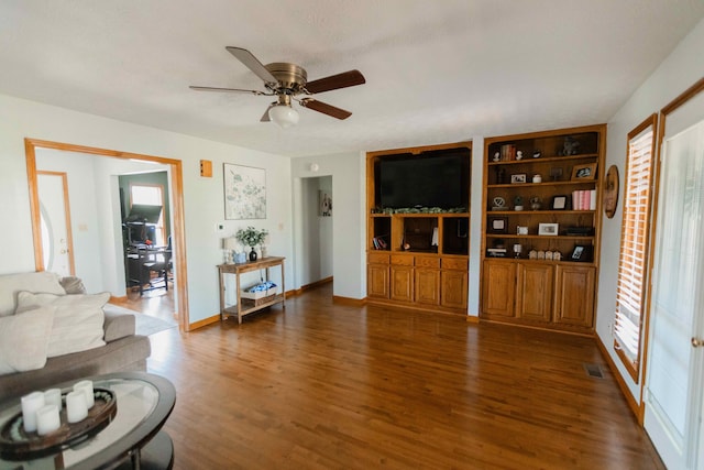 living room with built in shelves, a ceiling fan, wood finished floors, and visible vents