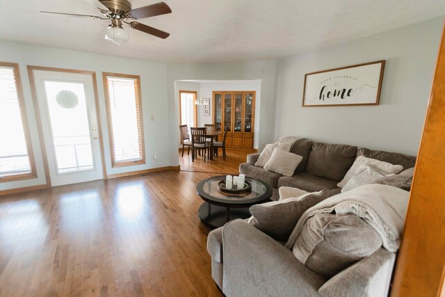 living area featuring ceiling fan, baseboards, and wood finished floors