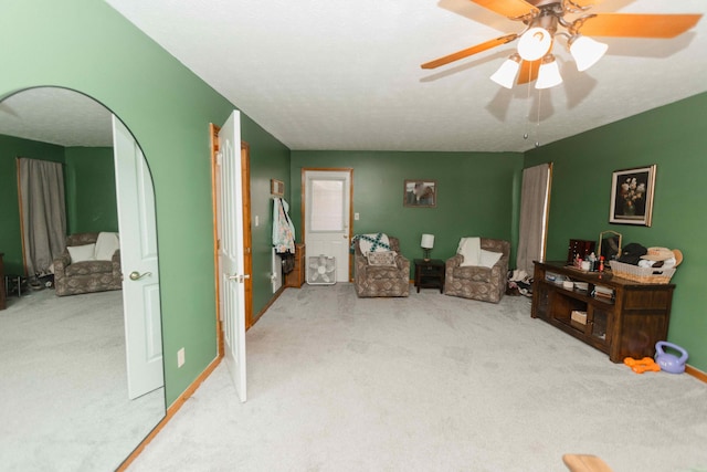 sitting room with a ceiling fan and carpet