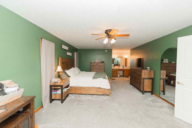 bedroom featuring light carpet, a ceiling fan, and ensuite bathroom