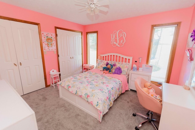 bedroom featuring ceiling fan, multiple closets, light colored carpet, and multiple windows