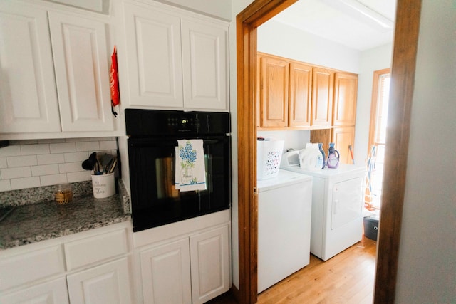 washroom with cabinet space, light wood finished floors, and separate washer and dryer