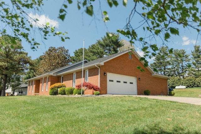 view of side of home with driveway, brick siding, a yard, and a garage