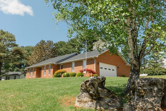 single story home with an attached garage, a front lawn, and brick siding