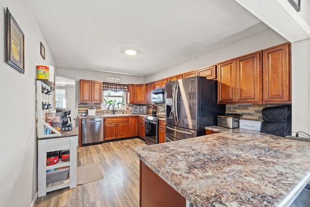 100 Lair St, Mount Vernon, KY 40456 - kitchen with appliances with stainless steel finishes, a peninsula, backsplash, brown cabinets, and light wood finished floors