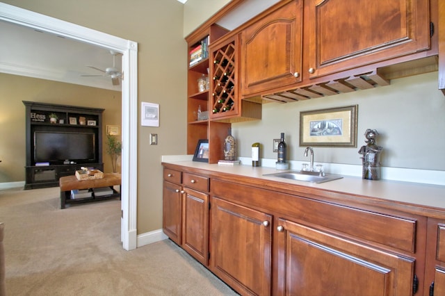 bar featuring ceiling fan, light colored carpet, a sink, baseboards, and wet bar