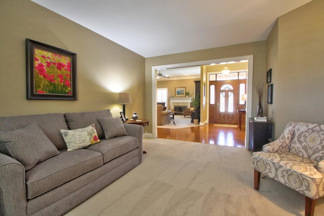 carpeted living room with baseboards, a ceiling fan, and a glass covered fireplace