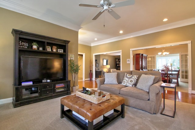 carpeted living room featuring recessed lighting, baseboards, ornamental molding, and ceiling fan with notable chandelier