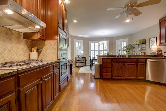 kitchen with ceiling fan, decorative backsplash, appliances with stainless steel finishes, light wood-style floors, and under cabinet range hood