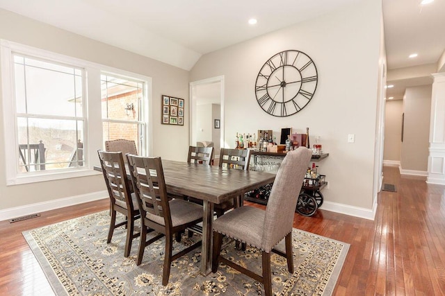 dining area with wood-type flooring, baseboards, vaulted ceiling, and visible vents