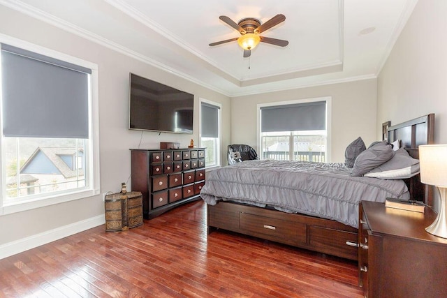 bedroom with crown molding, a ceiling fan, a raised ceiling, baseboards, and hardwood / wood-style flooring