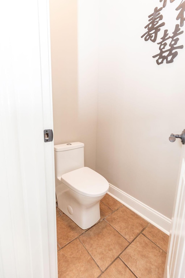 bathroom with tile patterned floors, baseboards, and toilet