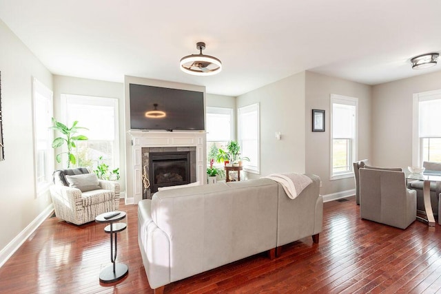 living room featuring a fireplace, dark wood-style floors, baseboards, and visible vents
