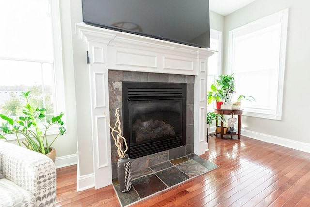 room details featuring a tile fireplace, wood finished floors, and baseboards