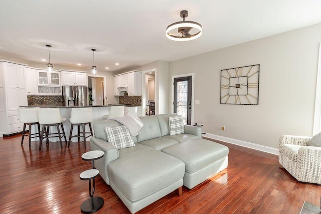 living room featuring recessed lighting, dark wood-style flooring, and baseboards