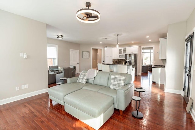 living room featuring dark wood-type flooring, baseboards, and recessed lighting