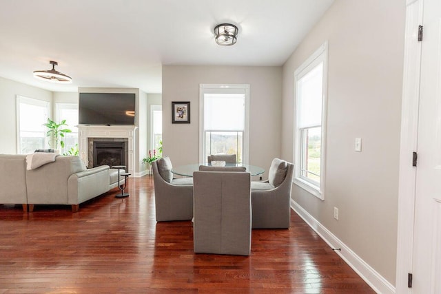 dining area featuring dark wood-type flooring, baseboards, and a fireplace